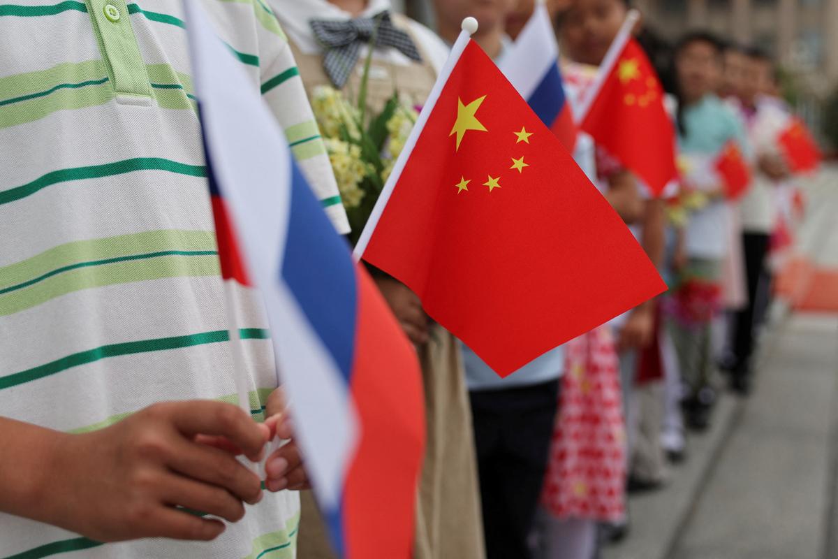 Children hold Russian and Chinese flags ahead of a welcoming ceremony for Russian President Vladimir Putin at the Great Hall of the People in Beijing, China May 20, 2026. REUTERS/Maxim Shemetov/Pool