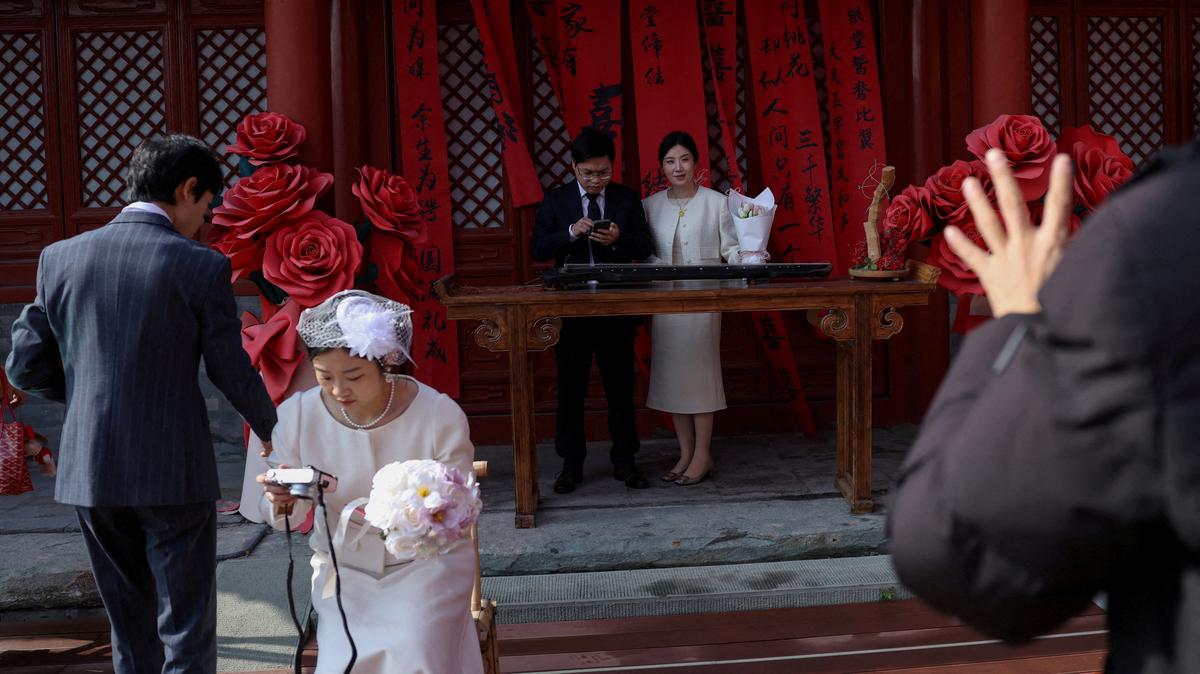 FILE PHOTO: Newlywed couples pose for pictures at the Huguo Guanyin Temple, an outdoor marriage registration site in Beijing, China, October 28, 2025. REUTERS/Tingshu Wang/File Photo