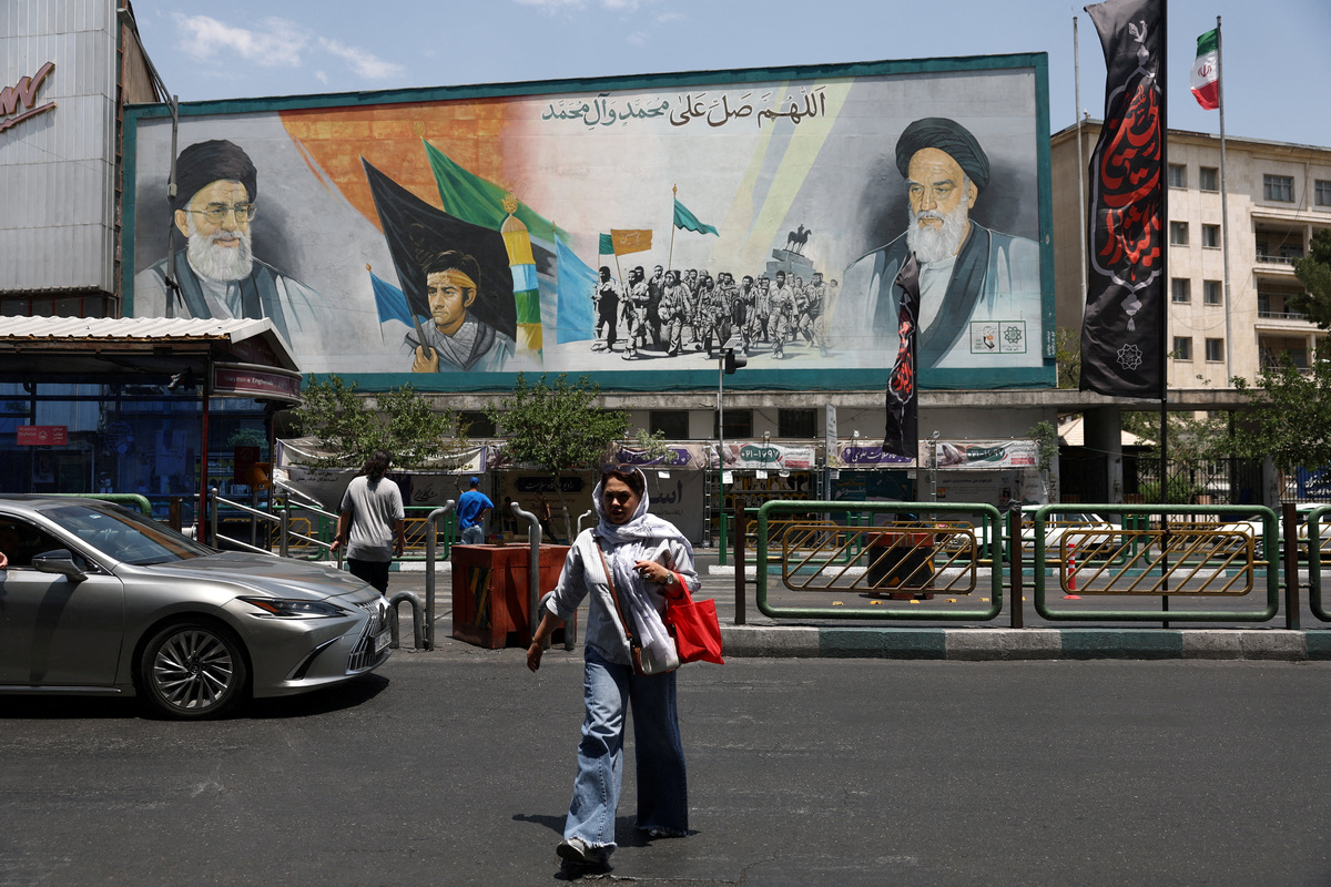 A woman walks near a mural depicting the late leader of the Islamic Revolution, Ayatollah Ruhollah Khomeini, and Iran's late Supreme Leader Ayatollah Ali Khamenei, on a street in Tehran, Iran, June 18, 2026. Majid Asgaripour/WANA (West Asia News Agency) via REUTERS