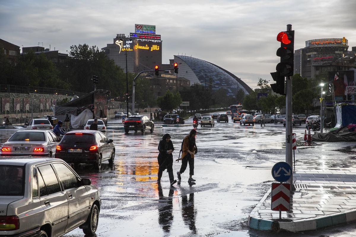 People cross a rainy intersection in Tehran, on Tuesday, April 28, 2026. Oil prices continued to climb on Tuesday, as peace talks between the United States and Iran appeared at an impasse, with negotiators deadlocked over proposals to reopen the Strait of Hormuz to tanker traffic and restrict Iran's nuclear program. (Arash Khamooshi/The New York Times)