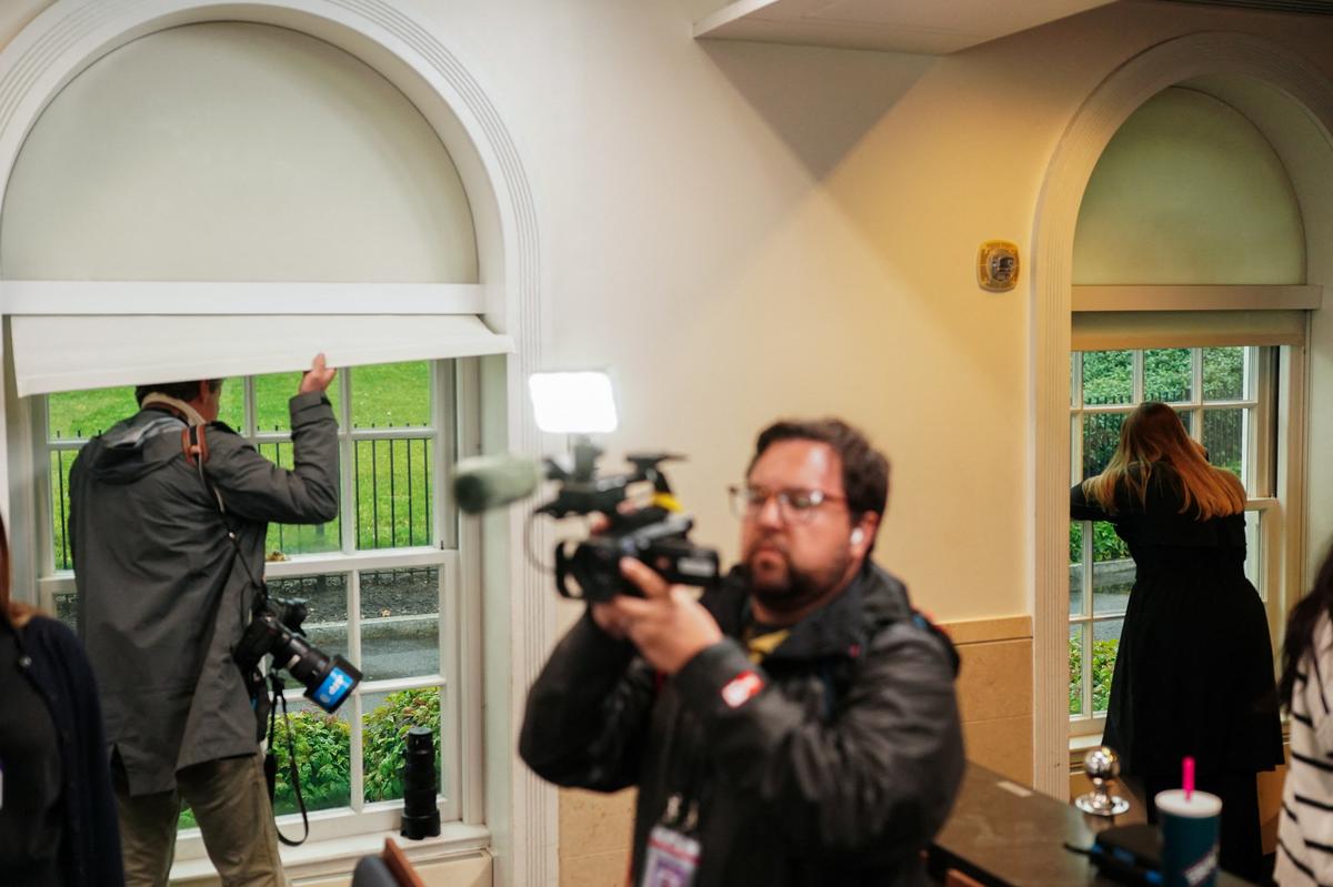 Journalists look out of windows in the White House press briefing room after alleged gunshots were heard nearby in Washington, D.C., U.S., May 23, 2026. REUTERS/Nathan Howard