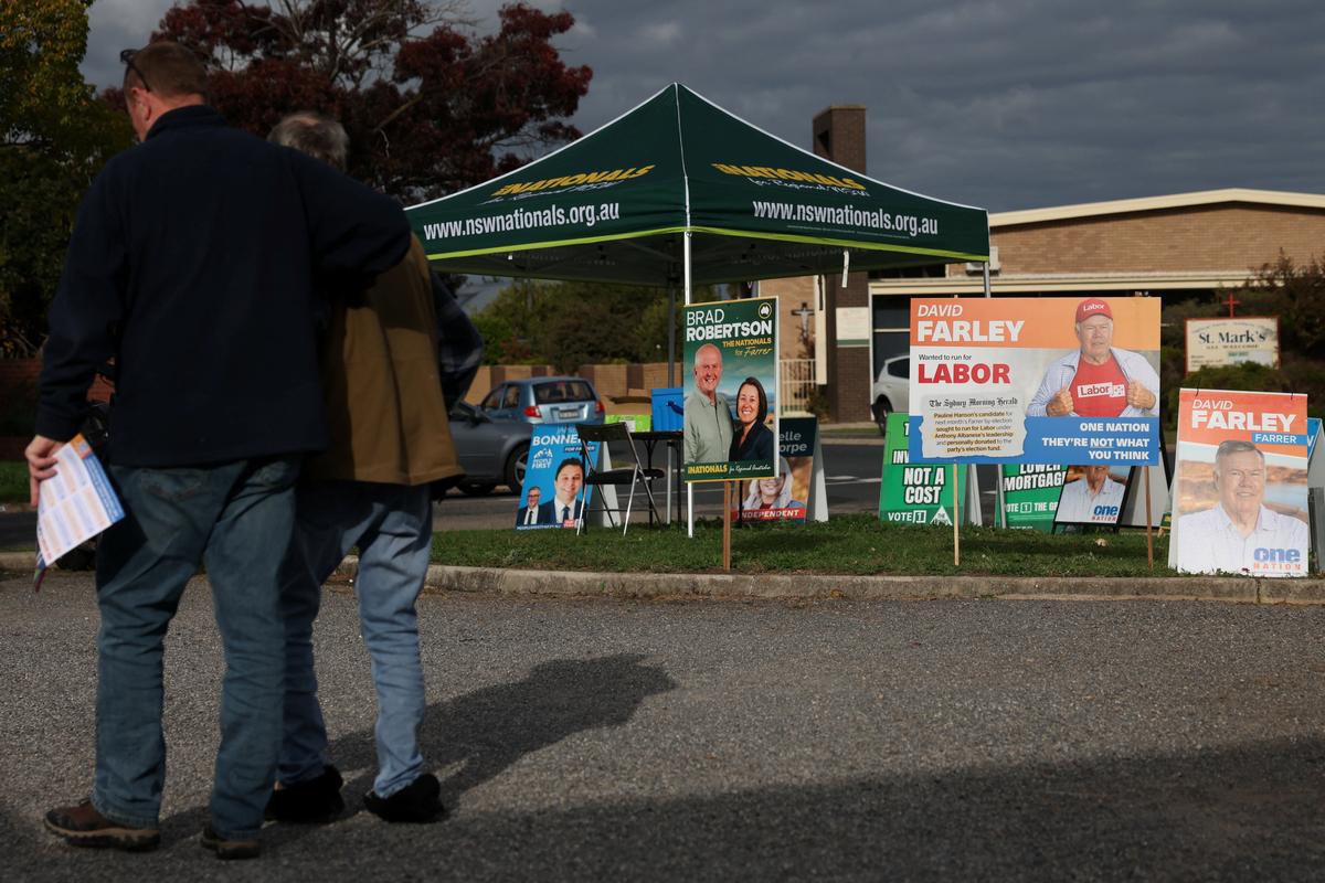 People walk past campaign signs depicting One Nation candidate David Farley are displayed outside a pre-polling centre ahead of the Farrer by-election in Albury, Australia, May 6, 2026. REUTERS/Hollie Adams