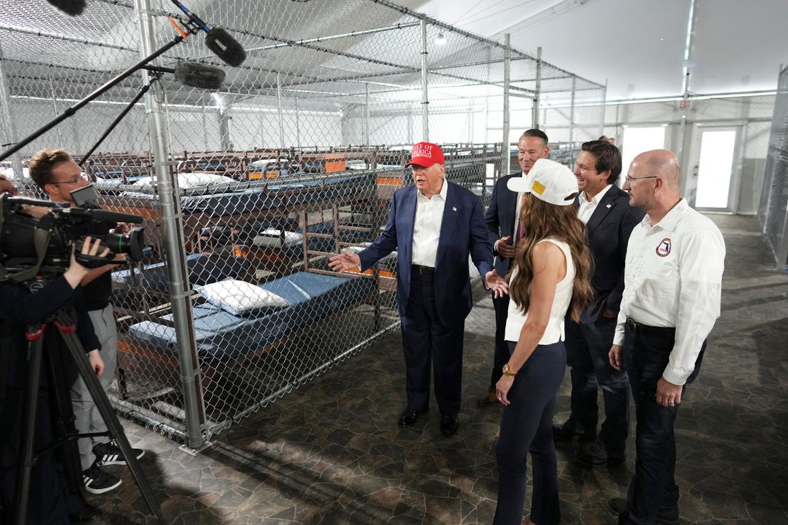 President Donald Trump speaks while touring a newly-constructed area for a detention camp with Homeland Security Secretary Kristi Noem, foreground, and Florida Gov. Ron DeSantis, second from right, after arriving at Dade-Collier Training and Transition Airport in Ochopee, Fla., on Tuesday, July 1, 2025. (Doug Mills/The New York Times)