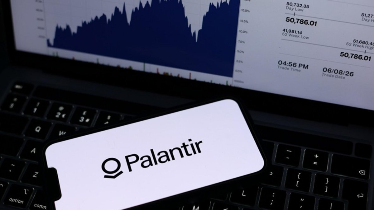 The Palantir logo is displayed on a mobile phone alongside a stock market graph displayed on a laptop screen in Liverpool, Britain, 09 June 2026. Photo by ADAM VAUGHAN / EPA
