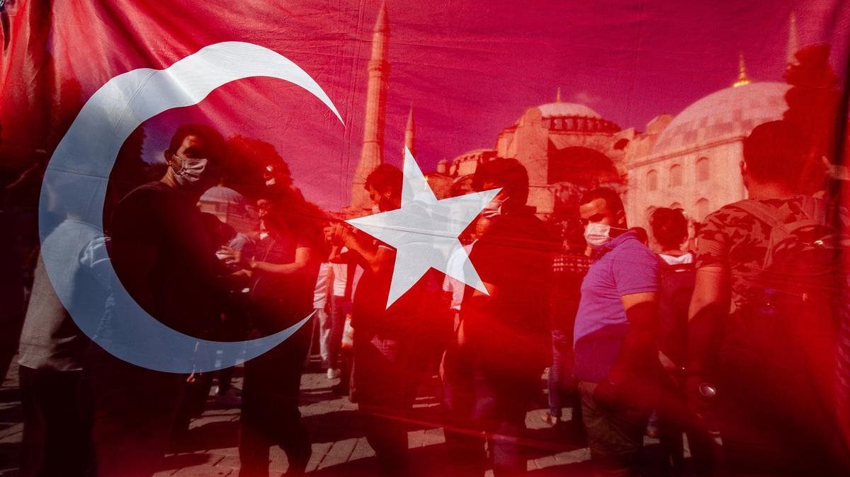 People stand behind a Turkish national flag in front of Hagia Sophia in Istanbul.