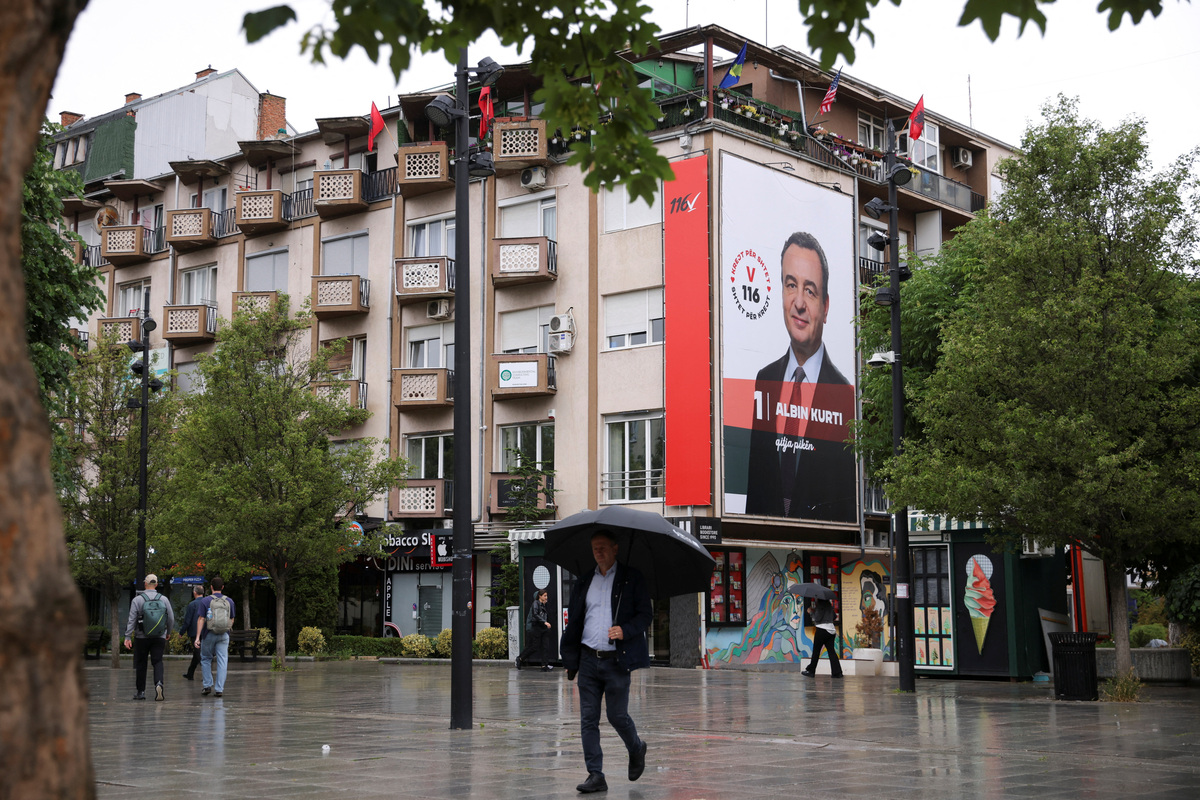 People walk near an election poster showing Prime Minister of Kosovo and Levizja Vetevendosje (Movement for Self-Determination) party leader Albin Kurti, in Pristina, Kosovo, June 4, 2026. Kosovo is to hold a snap parliamentary election, the third in just over a year, after parliament failed to elect a new head of state. REUTERS/Valdrin Xhemaj