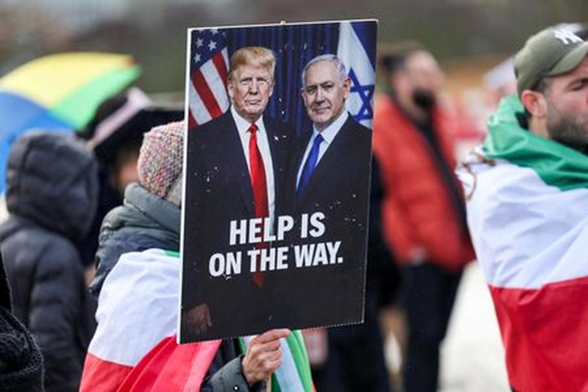 FILE PHOTO: A person holds a placard with a picture of U.S. President Donald Trump alongside Israeli Prime Minister Benjamin Netanyahu, as protesters gather near the United Nations office, on the day of the second round of nuclear talks between U.S. and Iran, in Geneva, Switzerland, February 17, 2026. REUTERS/Pierre Albouy/File Photo
