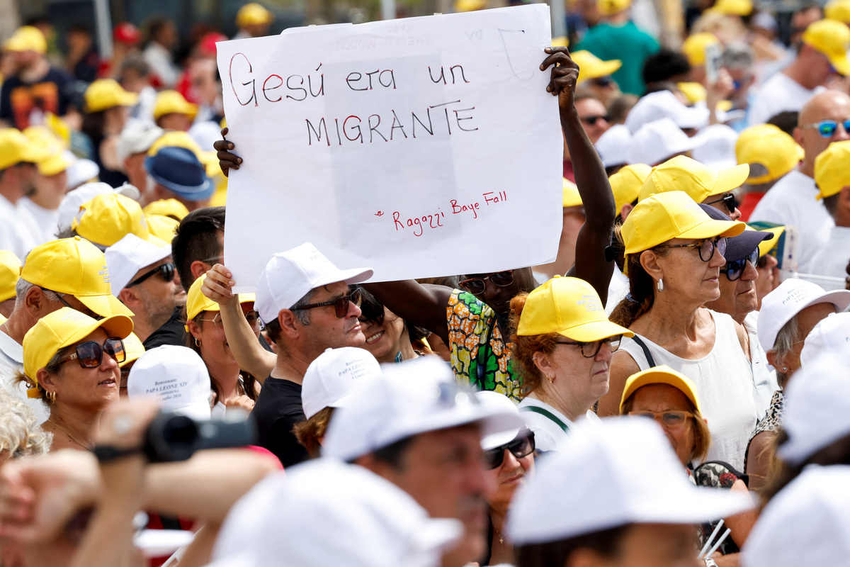 A person holds a sign reading: "Jesus was an immigrant", amid a crowd of faithful gathered for the Holy Mass celebrated with Pope Leo, as he visits the island of Lampedusa, a key entry point for migrants crossing the Mediterranean Sea, during a pastoral trip, Italy, July 4, 2026. REUTERS/Remo Casilli