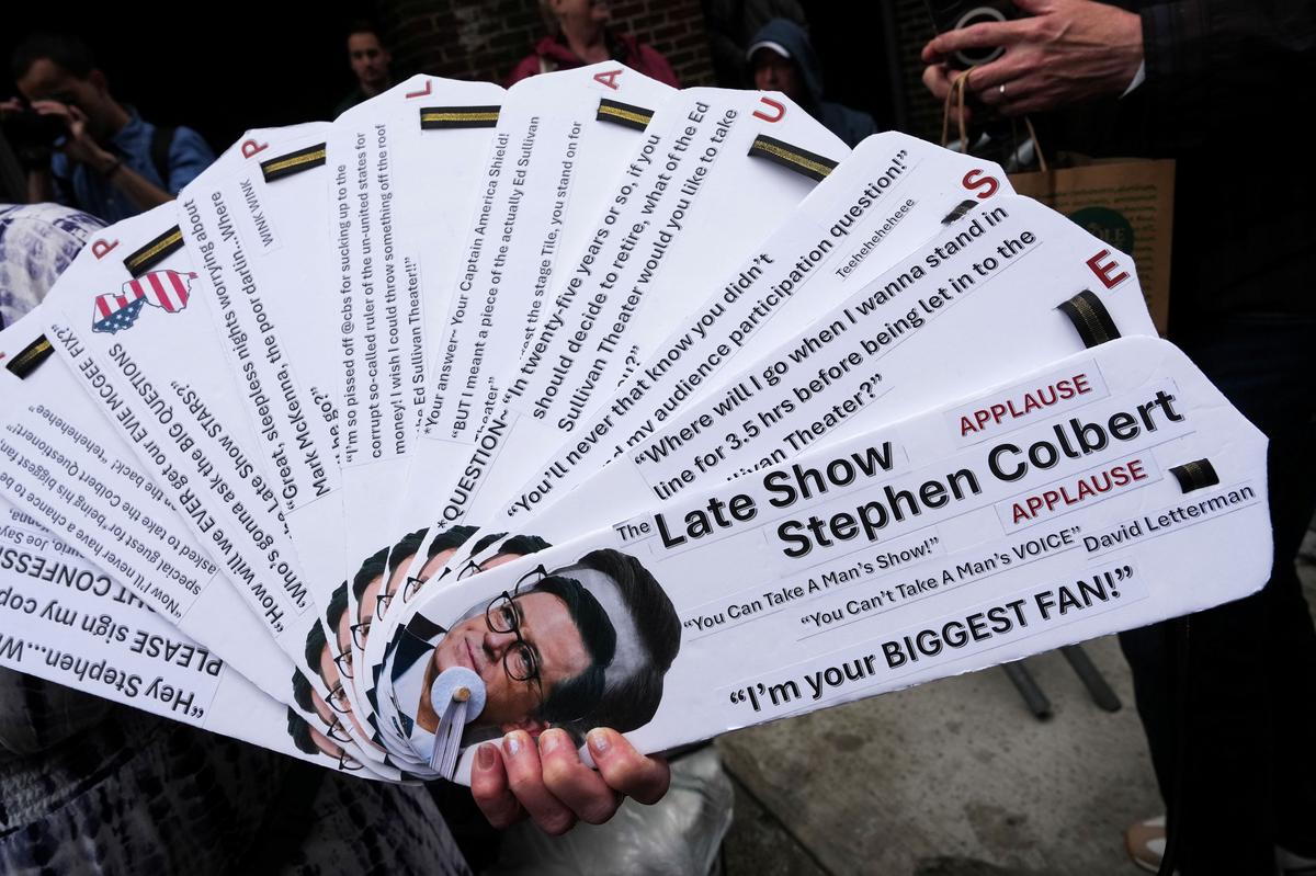 A person holds signs outside of the Ed Sullivan Theater before the taping of the final episode of the "The Late Show" with Stephen Colbert, in New York City, U.S., May 21, 2026. REUTERS/Adam Gray