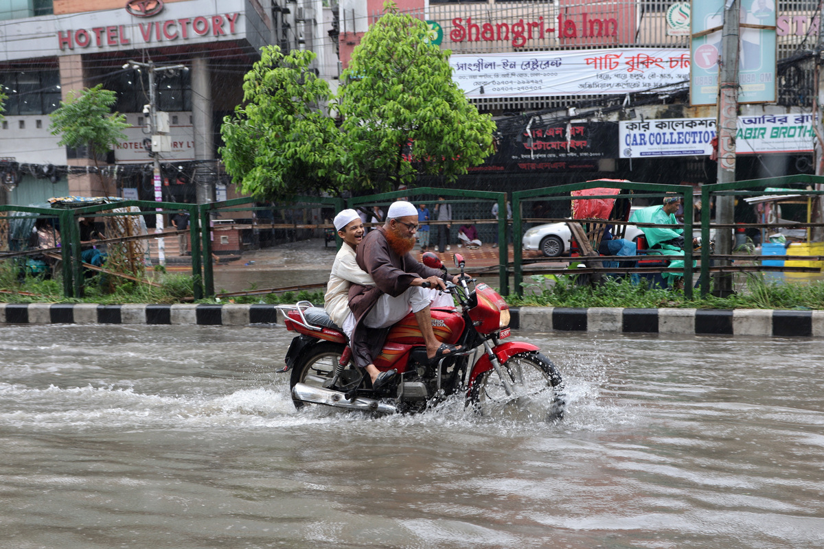 A child reacts while riding pillion on a motorcycle through a waterlogged street after heavy rainfall in Dhaka, Bangladesh, July 10, 2026. REUTERS/Mohammad Ponir Hossain