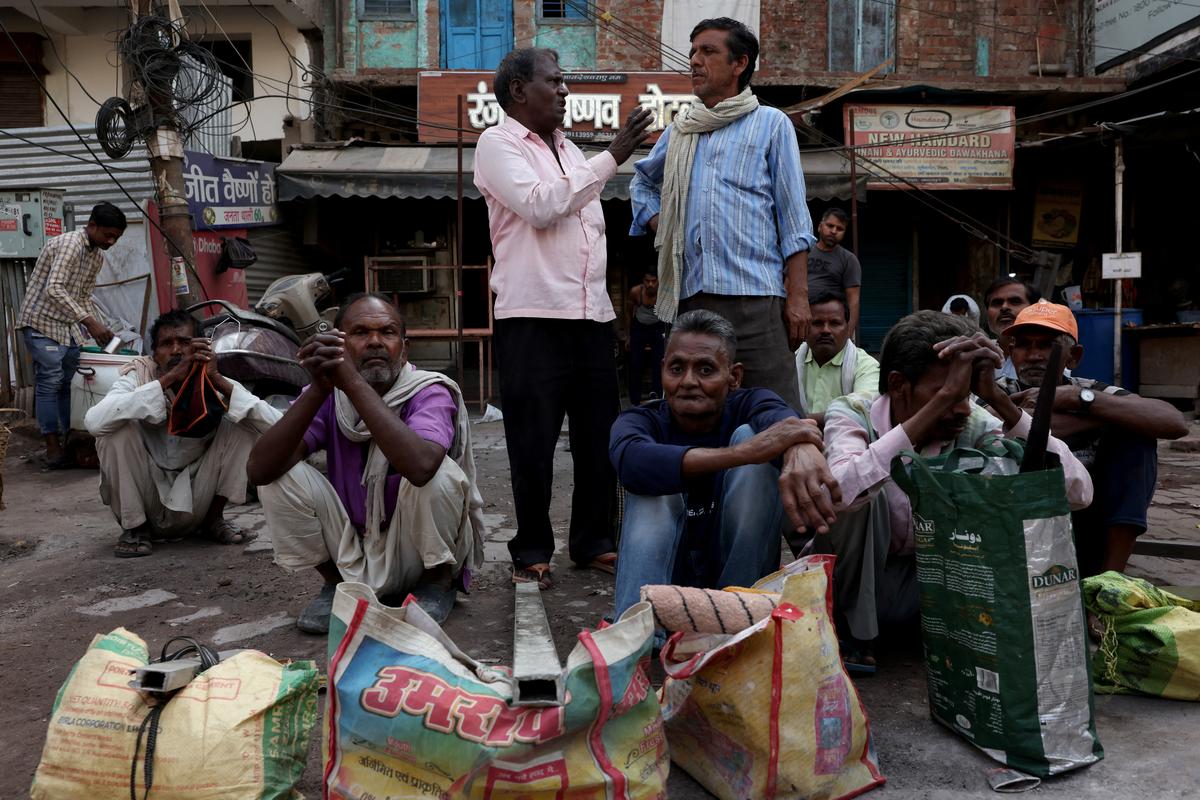 Labourers sit at a market intersection as they wait for people to hire them for work in Kanpur, India, May 14, 2026. REUTERS/Bhawika Chhabra
