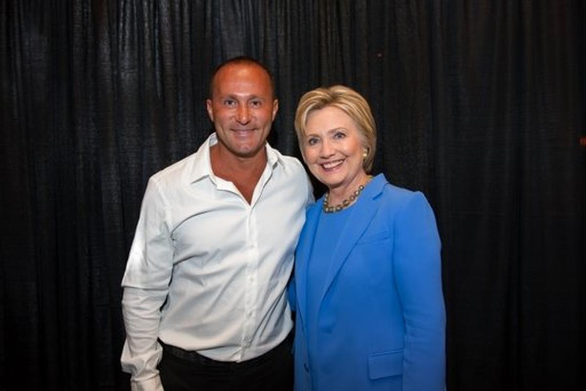 Esta imagen del portal digital del presidente ejecutivo de Allied Wallet, Ahmad Khawaja  lo muestra posando con Hillary Clinton. AP