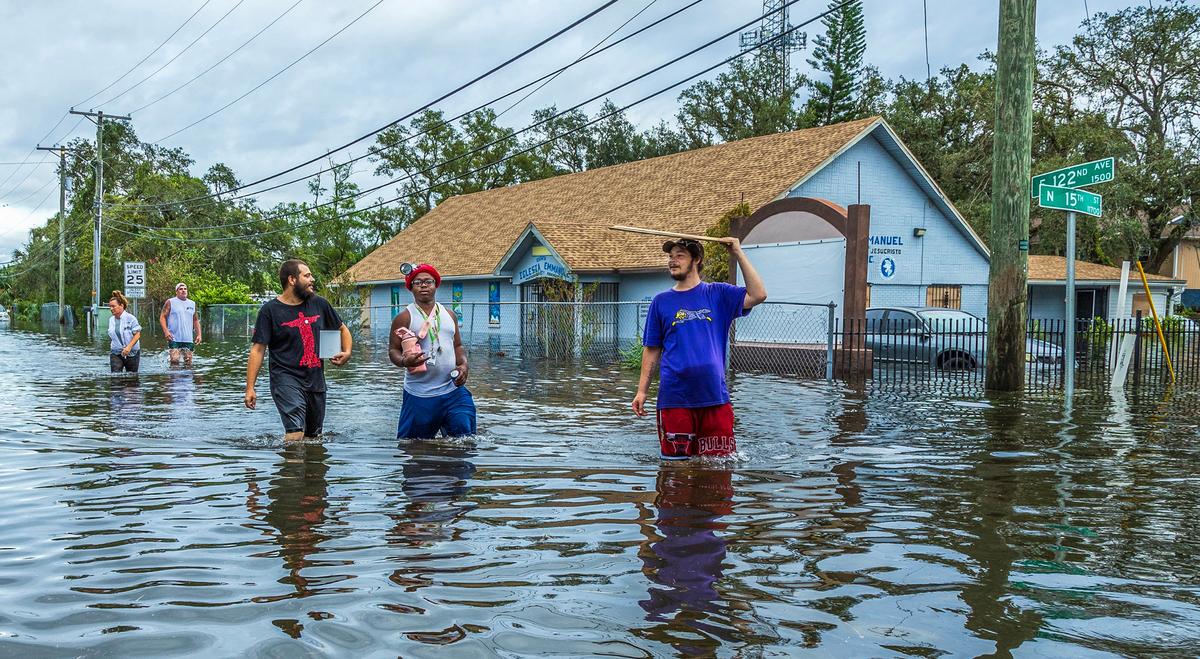 Residentes caminan por una calle inundada en el norte de Tampa, el jueves 10 de octubre de 2024, un día después de que el huracán Milton cruzara la costa del Golfo de Florida.