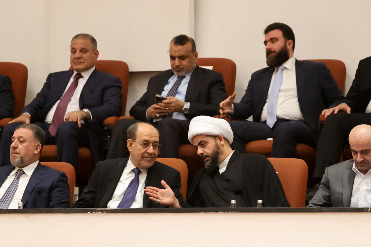 FILE PHOTO: Qais al-Khazali, head of the Asaib Ahl al-Haq group, speaks with former Iraqi Prime Minister Nouri al-Maliki during a parliamentary session to vote on a new government headed by Ali al-Zaidi at the parliament headquarters in Baghdad, Iraq, May 14, 2026. REUTERS/Ahmed Saad/File Photo