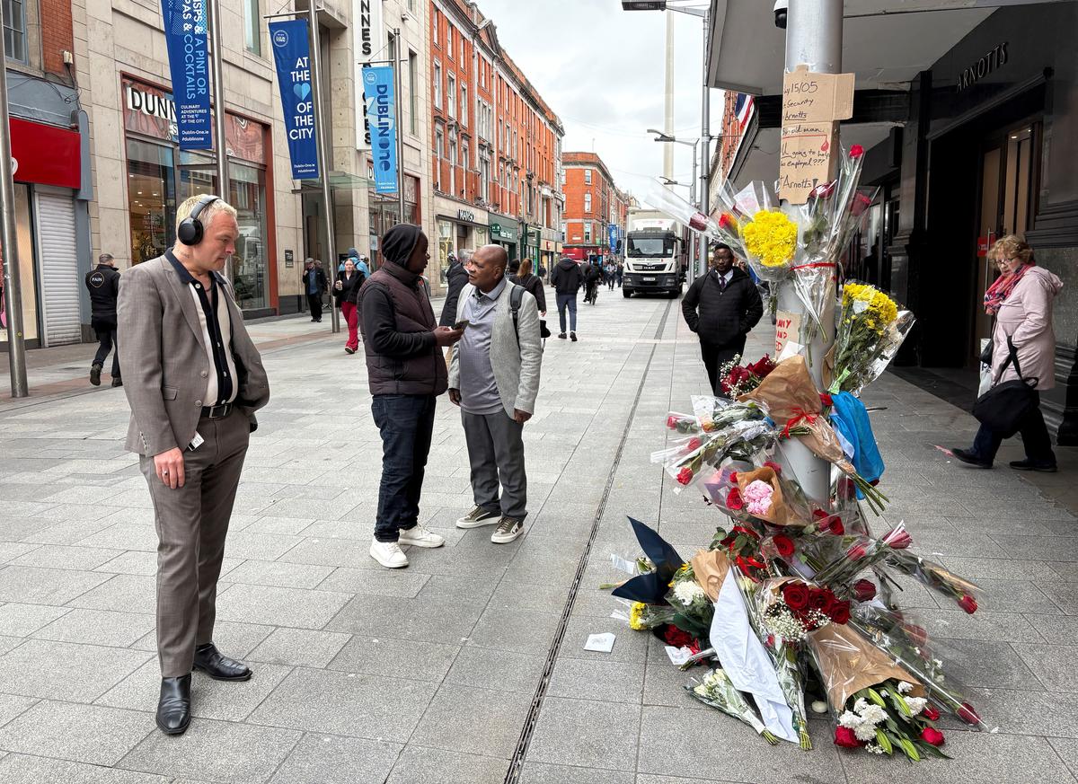 People stand near flowers laid outside a department store on Henry Street where a Congolese-born man, Yves Sakila, was restrained by security guards last week and later pronounced dead in hospital, in Dublin, Ireland, May 20, 2026. REUTERS/Conor Humphries