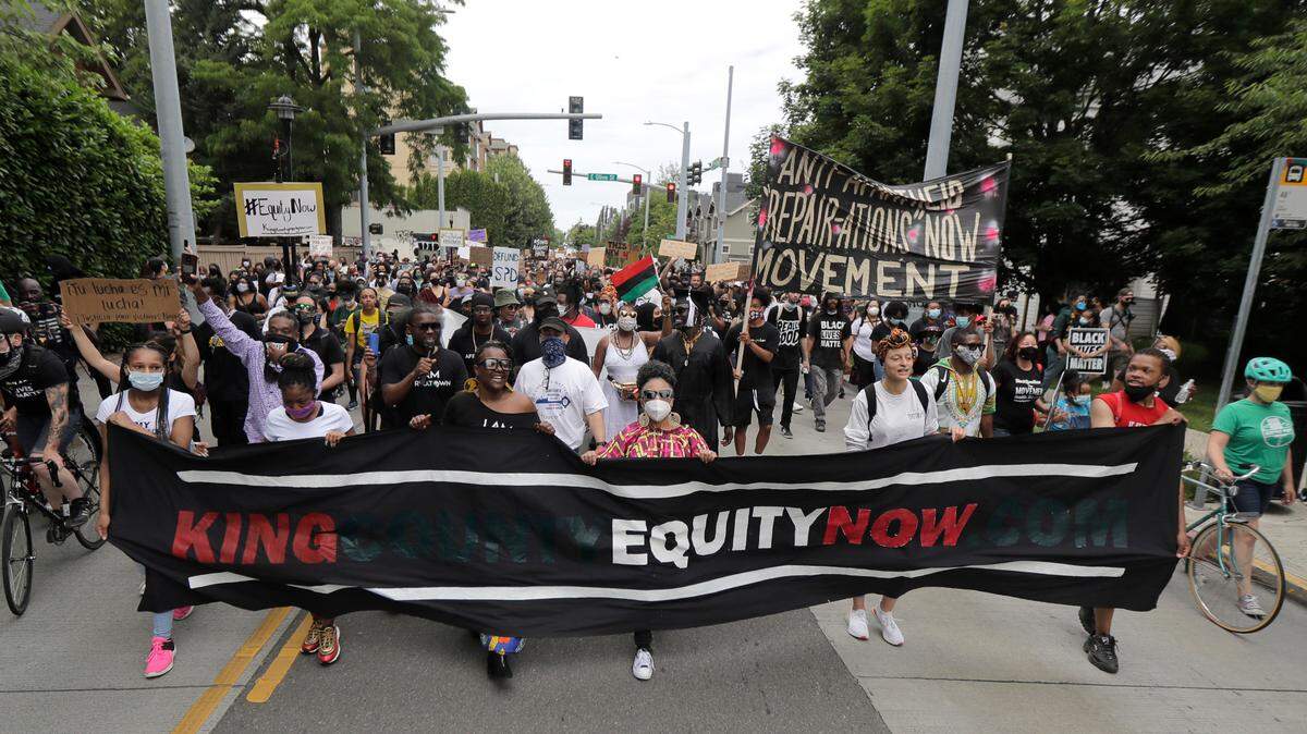 FILE - In this June 19, 2020, file photo, people taking part in a Juneteenth march travel down 23rd Ave. in Seattle. President Joe Biden this week signed legislation establishing a new federal holiday commemorating the end of slavery – a move lawmakers made for Washington state earlier this year. Washington Gov. Jay Inslee last month signed a measure making Juneteenth a legal state paid holiday, starting in 2022. (AP Photo/Ted S. Warren, File)