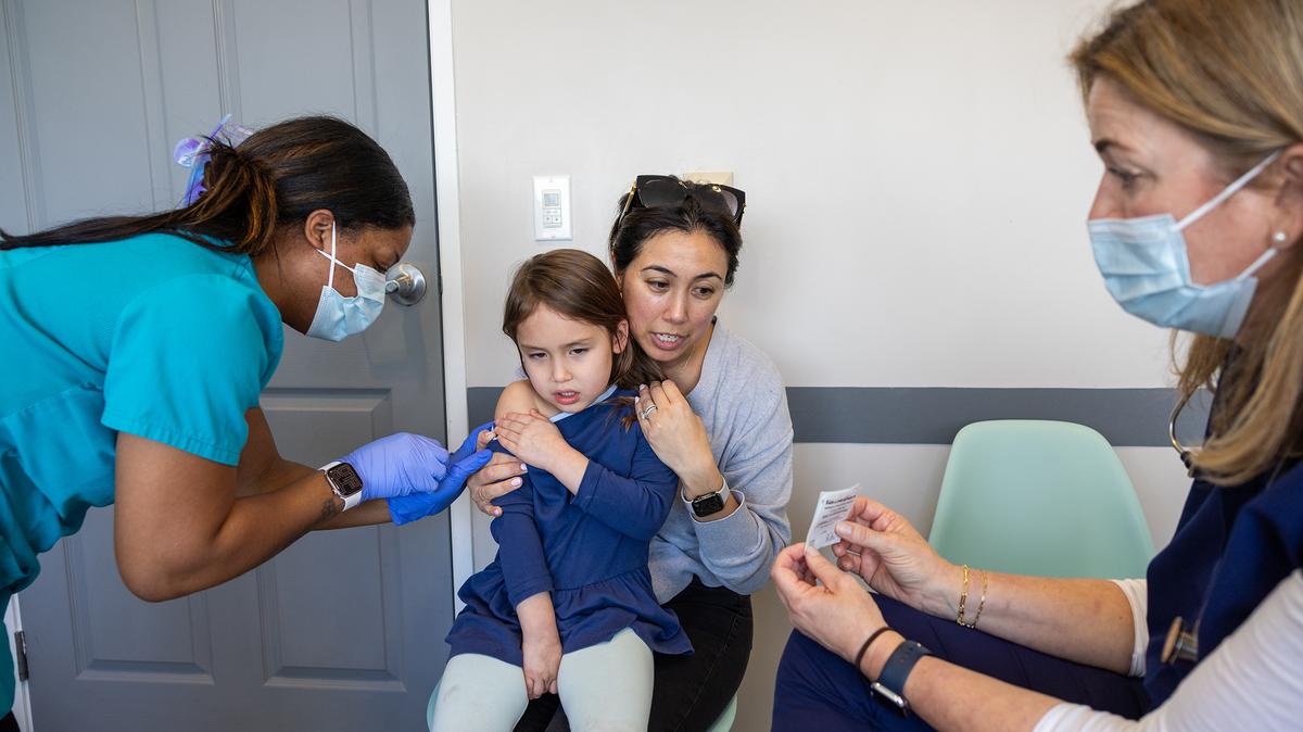 Dr. Neville Anderson, right, tries to distract Perry Roj, 4, while nurse Breanna Kirby gives her a DTaP polio vaccination. Her mom, Devin Homsey, holds her tight at Larchmont Pediatrics. (Allen J. Schaben/Los Angeles Times/TNS)