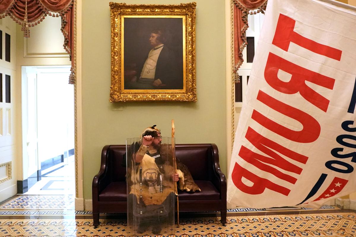FILE -- A rioter with a tactical shield sits in a hallway of the Capitol in Washington on Jan. 6, 2021, after supporters of President Donald Trump breached security and entered the building. Some Republicans in Congress seeing President Trump's personal agenda diverging from their political interests, vented their outrage about paying those who threatened their lives on Jan. 6. (Erin Schaff/The New York Times)