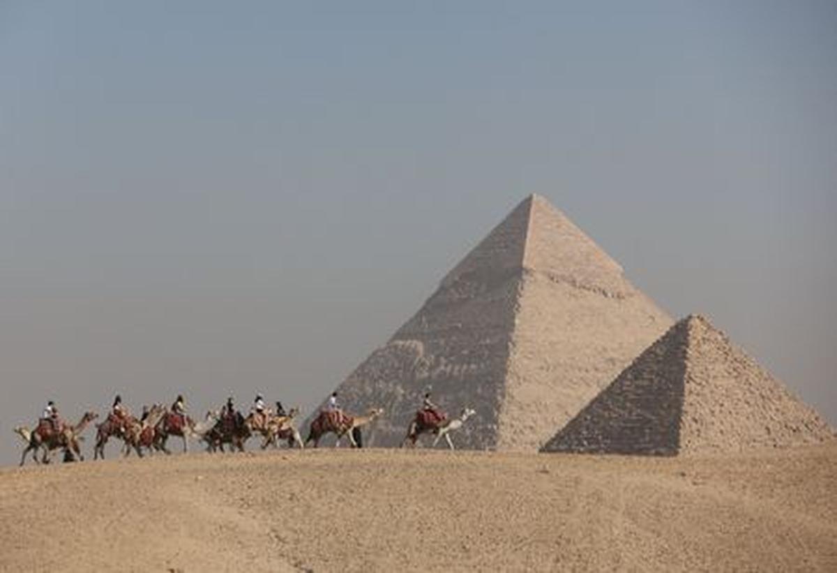 FILE PHOTO: Tourists ride camels in front of the Great Pyramids plateau in Giza, Egypt December 11, 2022. REUTERS/Amr Abdallah Dalsh/File Photo