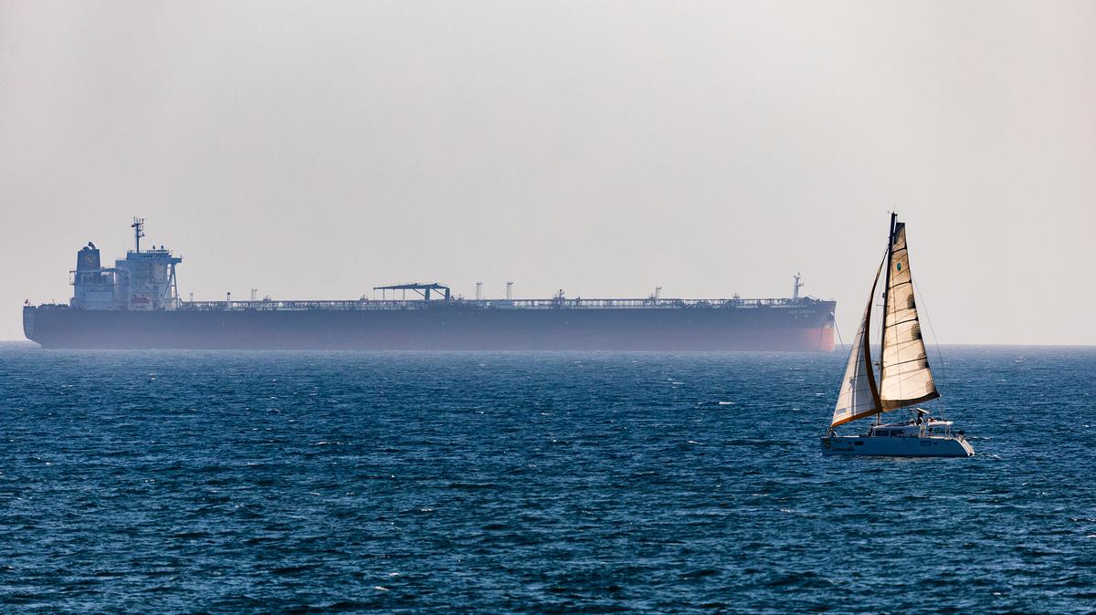A sailboat moves along the coast as the Hong Kong-flagged crude oil tanker New Corolla sits anchored in the distance off Huntington Beach, Calif., bound for the Port of Long Beach, on Friday, May 1, 2026. (Allen J. Schaben/Los Angeles Times/TNS)