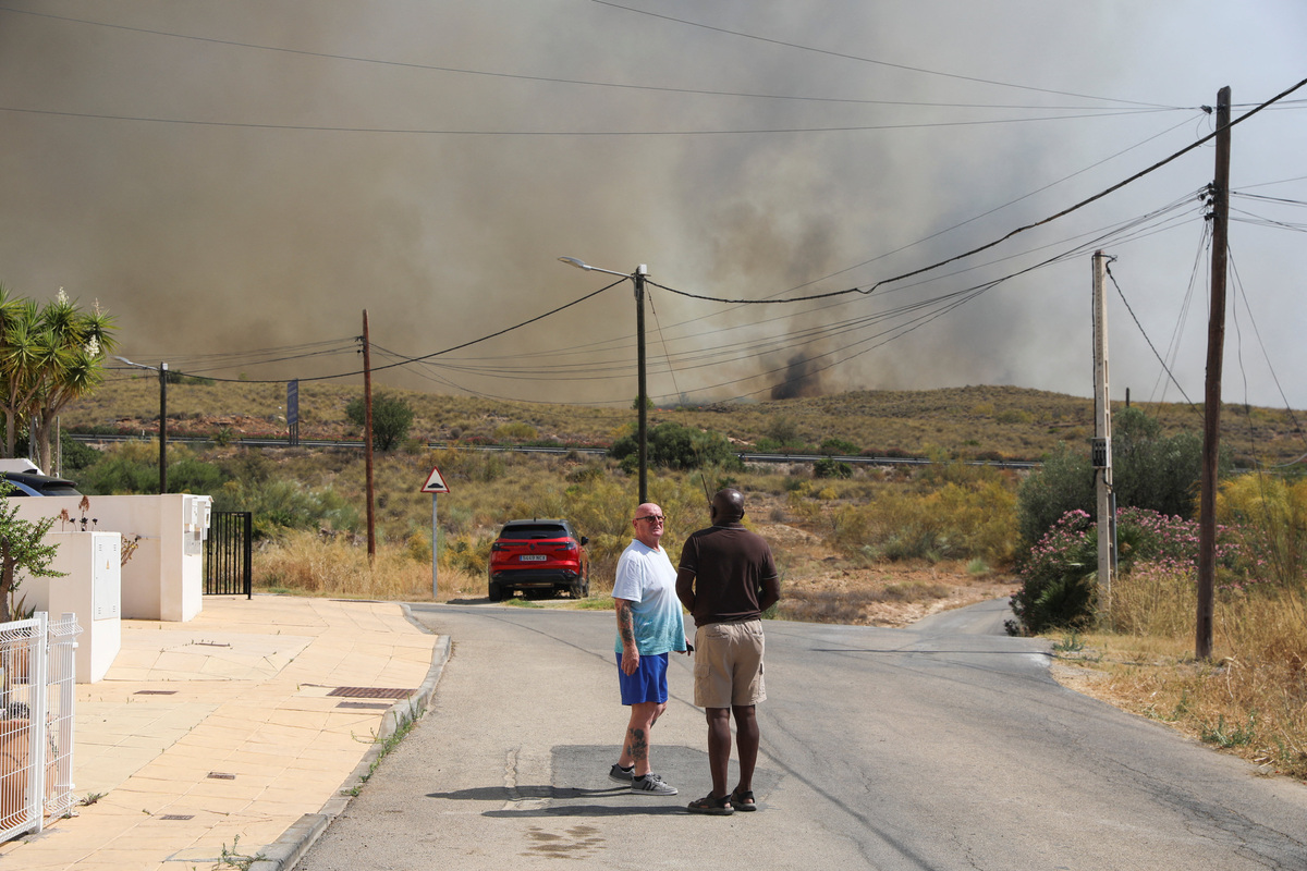 Residents talk as they get ready to leave their homes while smoke and flames rise during a wildfire in Los Gallardos, Almeria, Spain, July 10, 2026. REUTERS/Loyola Perez de Villegas Muniz