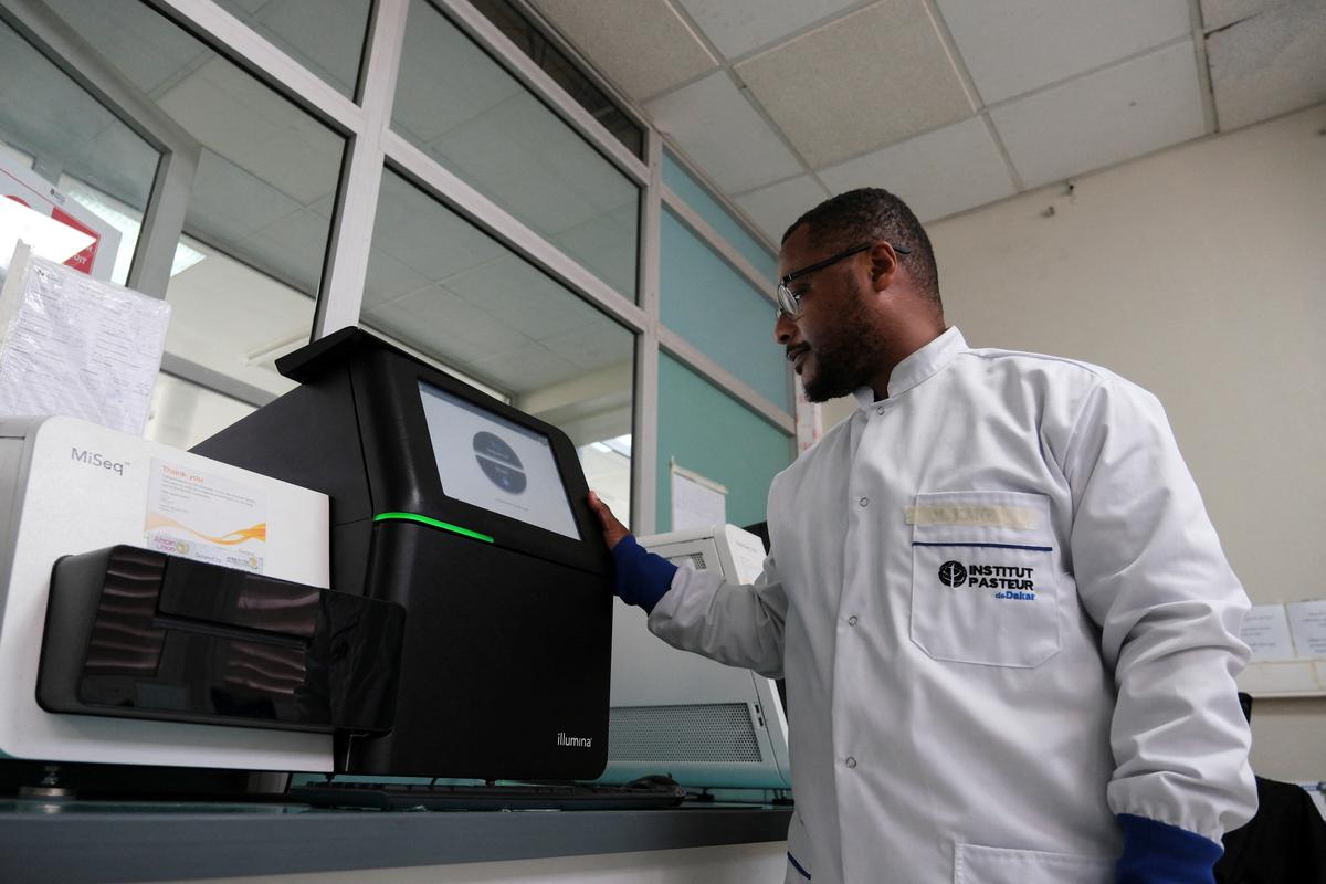 Dr. Moussa Moise Diagne, a virologist and head of the sequencing platform at Institut Pasteur, poses with one of the machines used to sequence the hantavirus genome during the coordinated response to the April 2026 outbreak, at Institut Pasteur in Dakar, Senegal, May 19, 2026. REUTERS/Ricci Shryock