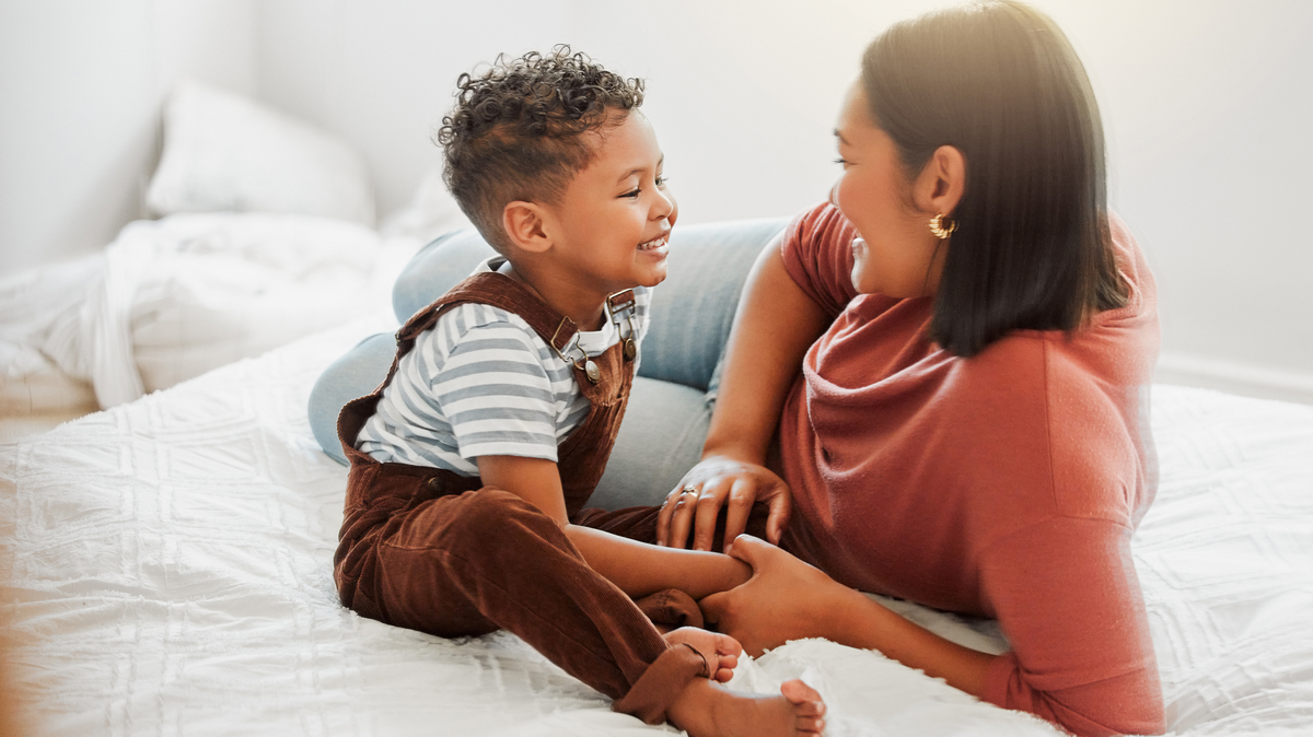 A loving mother with her son, teaching him to talk in a bedroom at home. 