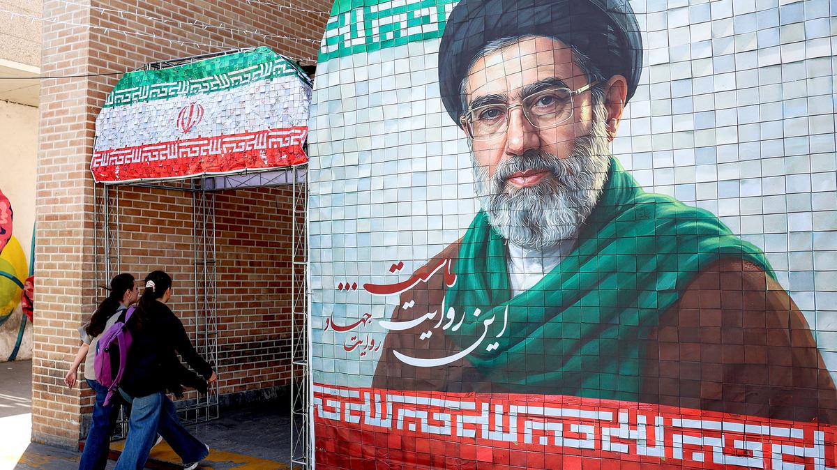 Women walk past a banner depicting Iran's current supreme leader Ayatollah Mojtaba Khamenei along a street Tehran on May 6, 2026. (-/AFP via Getty Images/TNS)