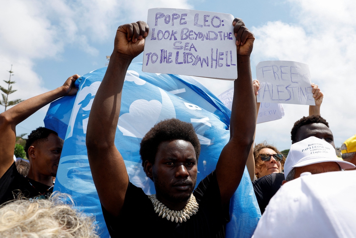 A man holds a sign bearing a message for Pope Leo during a Holy Mass celebrated by the pontiff on the island of Lampedusa, a key entry point for migrants crossing the Mediterranean Sea, during his pastoral visit, Italy, July 4, 2026. REUTERS/Remo Casilli