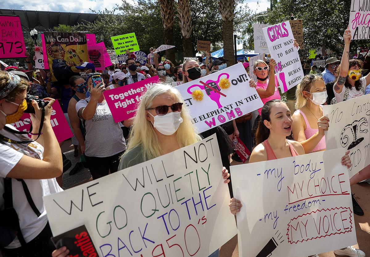 Participants wave signs as they walk to Orlando City Hall during the March for Abortion Access on Saturday, Oct. 2, 2021, in Orlando.
