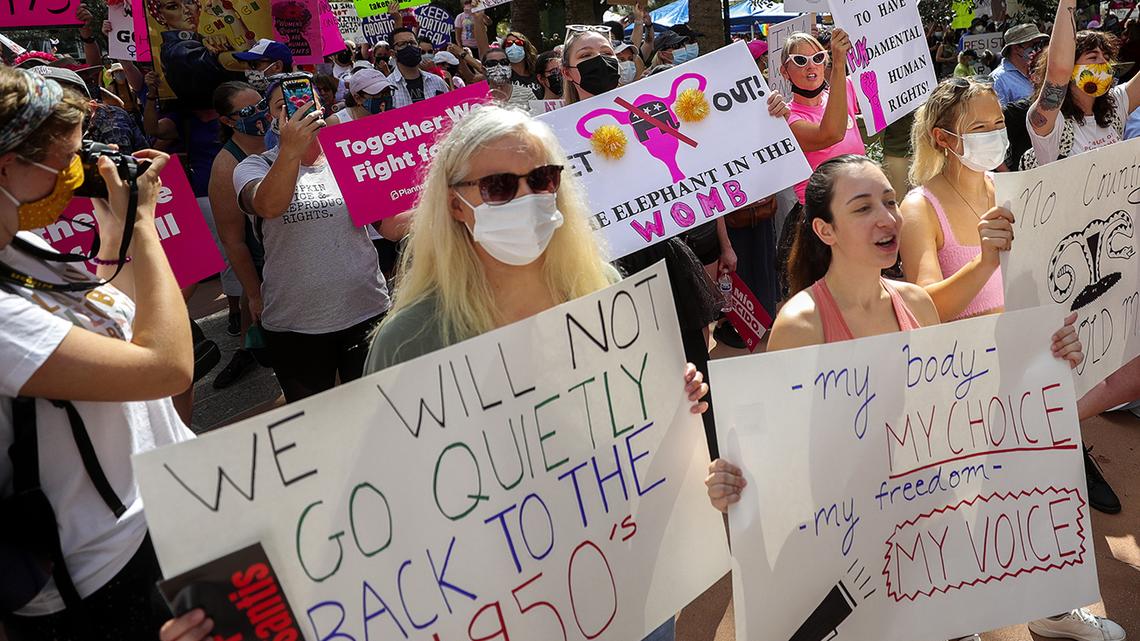 Participants wave signs as they walk to Orlando City Hall during the March for Abortion Access on Saturday, Oct. 2, 2021, in Orlando.