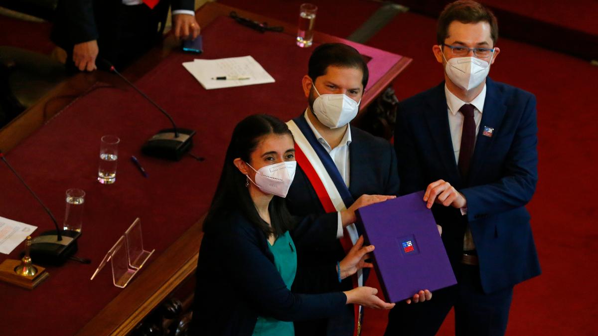 El presidente chileno Gabriel Boric, en el centro, sostiene el borrador final de la nueva constitución del país junto con los miembros de la Convención Constituyente, María Elisa Quinteros y Gaspar Domínguez, en Santiago, Chile, el lunes 4 de julio de 2022. (AP Foto/Luis Hidalgo)