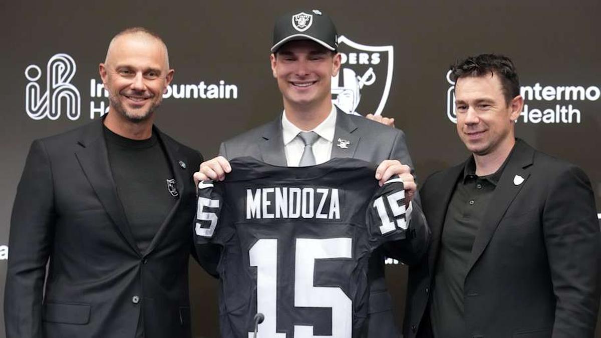  Apr 24, 2026; Henderson, NV, USA; Las Vegas Raiders quarterback Fernando Mendoza (center) poses with jersey at introductory press conference at Intermountain Health Performance Center flanked by general manager John Spytek (left) and head coach Klint Kubiak after being selected as the No. 1 pick in the 2026 NFL Draft. Mandatory Credit: Kirby Lee-Imagn Images | Kirby Lee-Imagn Images 