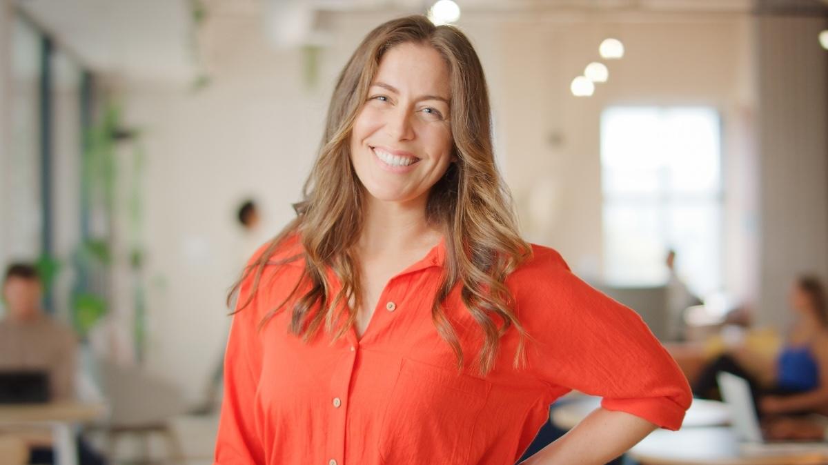 Portrait Of Smiling Mature Businesswoman Standing In Busy Open Plan Office