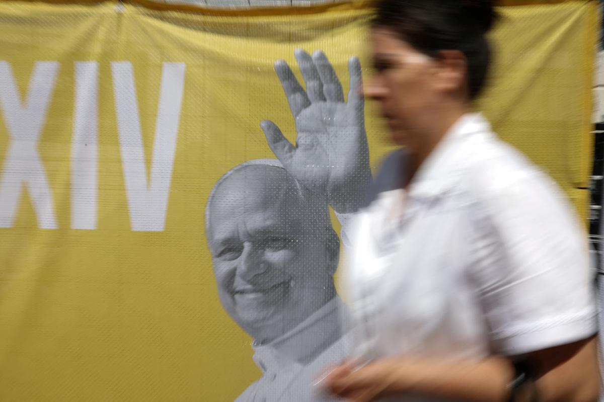 A women walks past a banner announcing the visit of Pope Leo XIV outside the Santiago Bernabeu Stadium in Madrid, Spain, June 2, 2026. REUTERS/Kacper Pempel