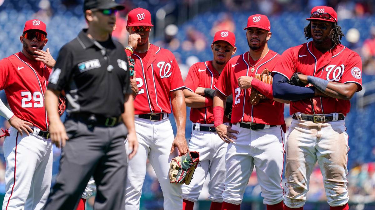 Members of the against the Washington Nationals watch as crew chief umpire Mark Wegner, second from left, decides a call during the fifth inning of a baseball game against the Pittsburgh Pirates at Nationals Park, Wednesday, June 29, 2022, in Washington. (AP Photo/Alex Brandon)