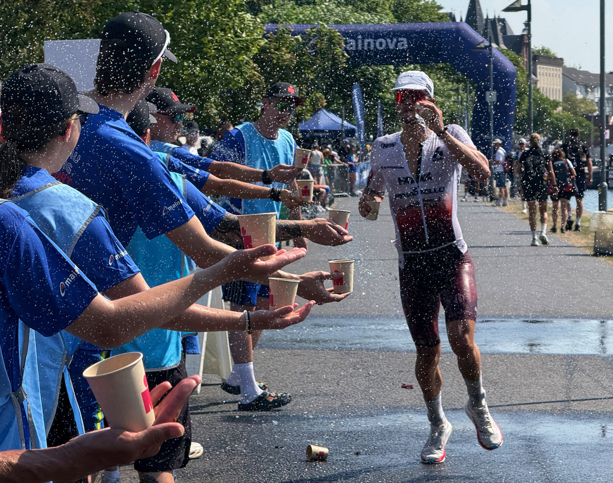 Volunteers offer drinks to an Ironman athlete during the ongoing heat wave in Frankfurt, Germany, June 28, 2026.   REUTERS/Timm Reichert