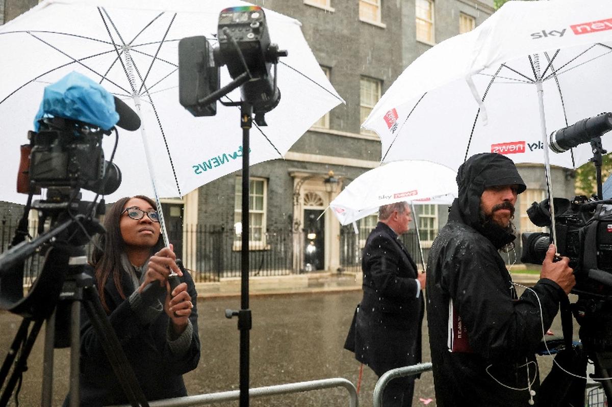 Members of the media shelter from the rain on Downing Street, following the resignation of Wes Streeting as British Health Secretary, in London, Britain, May 14, 2026. REUTERS/Hannah McKay