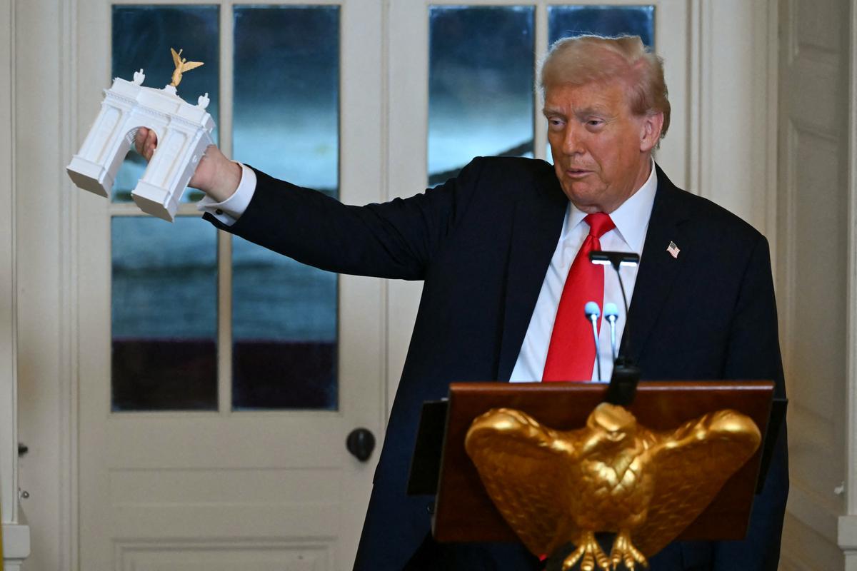  President Donald Trump holds up a model for a proposed Triumphal Arch at the White House on October 15, 2025. 