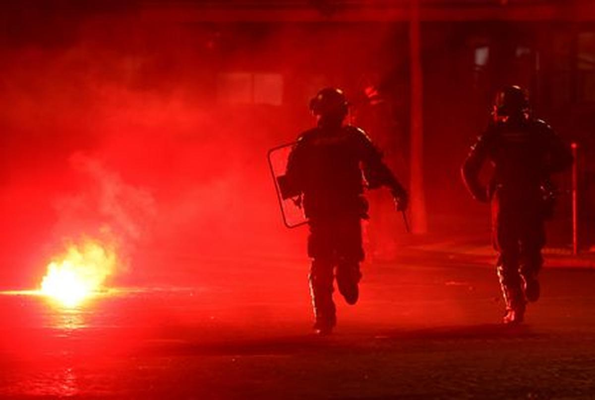 Soccer Football - UEFA Champions League -  Paris St Germain fans celebrate winning the UEFA Champions League - Paris, France - May 31, 2026 Police officers protect themselves from a flare after Paris St Germain won the UEFA Champions League REUTERS/Abdul Saboor