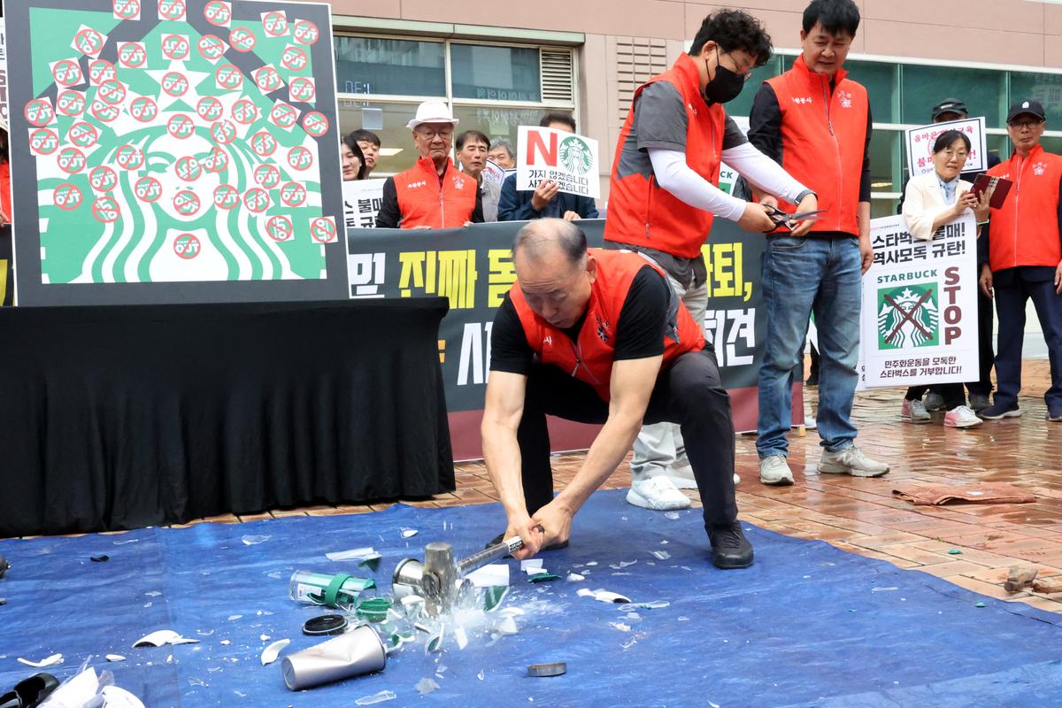 An activist smashes Starbucks tumblers and mugs during a protest against Starbucks' "Tank Day" campaign, which was launched on the same day as the anniversary of the May 18 Gwangju uprising, when the then military government sent in troops and tanks to suppress mass rallies for democracy, in Gwangju, South Korea, May 21, 2026.   Yonhap via REUTERS   THIS IMAGE HAS BEEN SUPPLIED BY A THIRD PARTY. NO RESALES. NO ARCHIVES. SOUTH KOREA OUT. NO COMMERCIAL OR EDITORIAL SALES IN SOUTH KOREA.