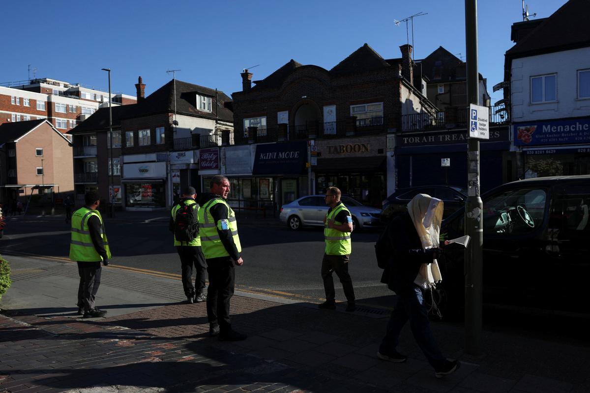 An Orthodox Jewish man walks past security personnel patrolling the street near the scene where a man was arrested on Wednesday following a stabbing incident in which two Jewish men were wounded in the Golders Green area, which is home to a large Jewish population, in London, Britain, April 30, 2026. REUTERS/Hannah McKay