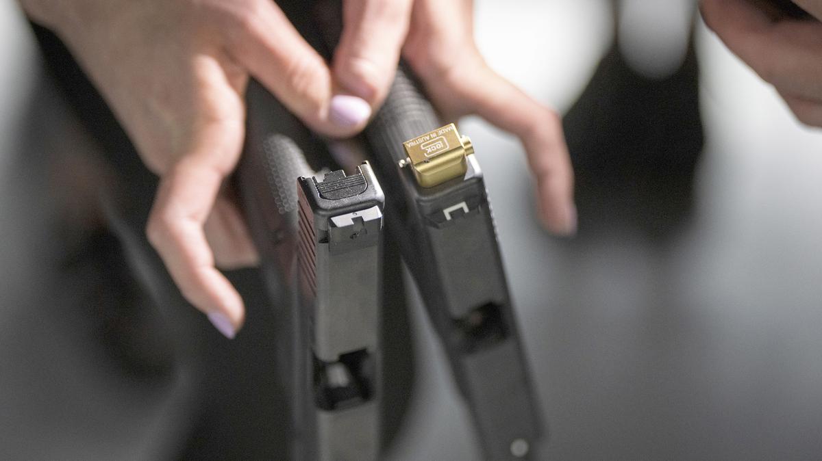 A member of the Minnesota U.S. Attorney's office holds a Glock pistol with an auto switch attached, at right, which converts the semi-automatic Glock pistol to function as a fully automatic firearm, next to one with no switch attached, at left, during a range demonstration held by the St. Paul Field Division of the Bureau of Alcohol, Tobacco, Firearms and Explosives for members of the Minnesota U.S. Attorney's office at the South Metro Public Safety Training Facility in Edina, Minnesota, on May 25, 2023. (Leila Navidi/The Minnesota Star Tribune/TNS)