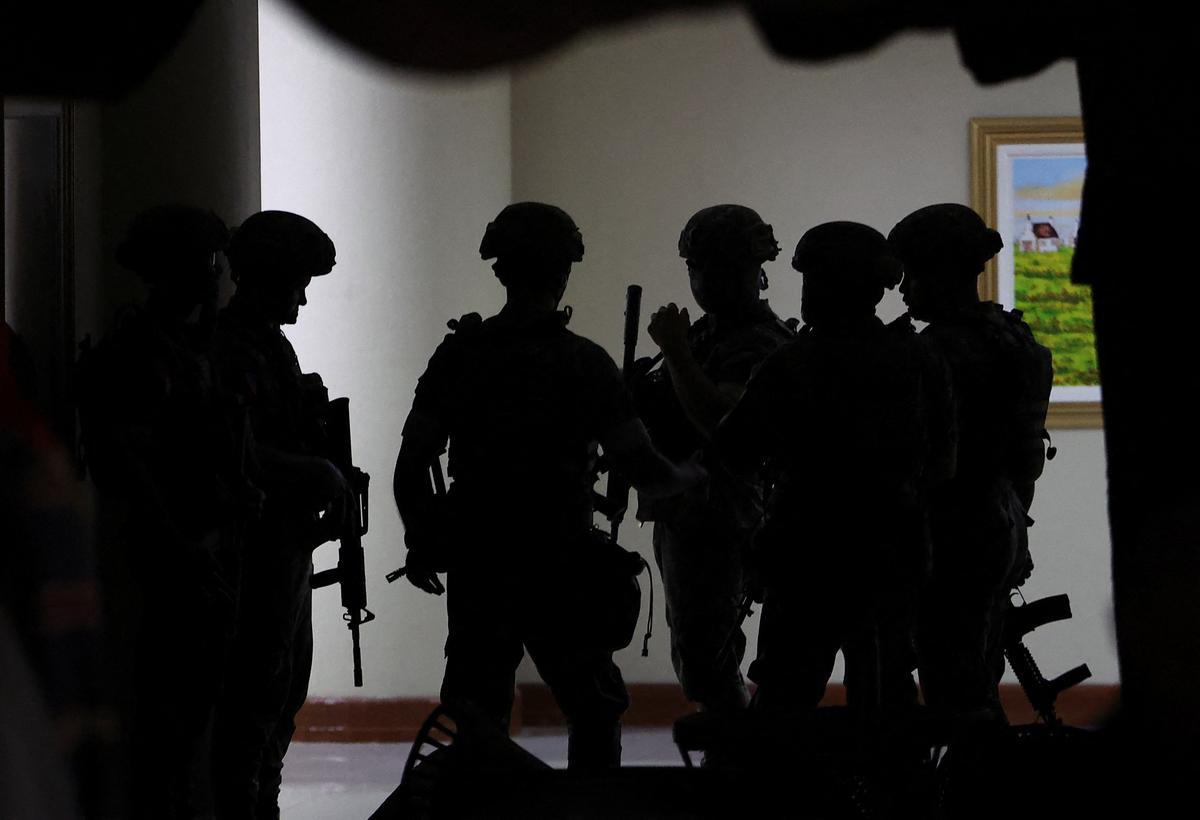 Military personnel in camouflage fatigues enter the Senate building where Philippine Senator Ronald "Bato" dela Rosa, the chief enforcer of former president Rodrigo Duterte's drug war, at the Senate, is under protective custody amid an International Criminal Court warrant, as more than a dozen gunshots were heard at the Philippine Senate on Wednesday, and people were told to run for cover, according to a Reuters witness, in Pasay City, Metro Manila, Philippines, May 13, 2026. REUTERS/Eloisa Lopez