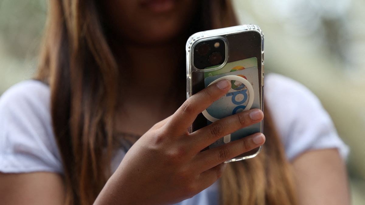 A teenager poses holding a mobile phone as law banning social media for users under 16 in Australia takes effect, in Sydney, Australia, December 10, 2025. REUTERS/Hollie Adams