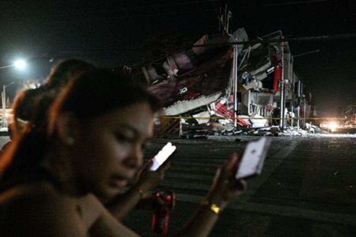 People use their phones near a collapsed building following the magnitude 7.8 quake in General Santos, southern Philippines, June 8, 2026. REUTERS/Noel Celis