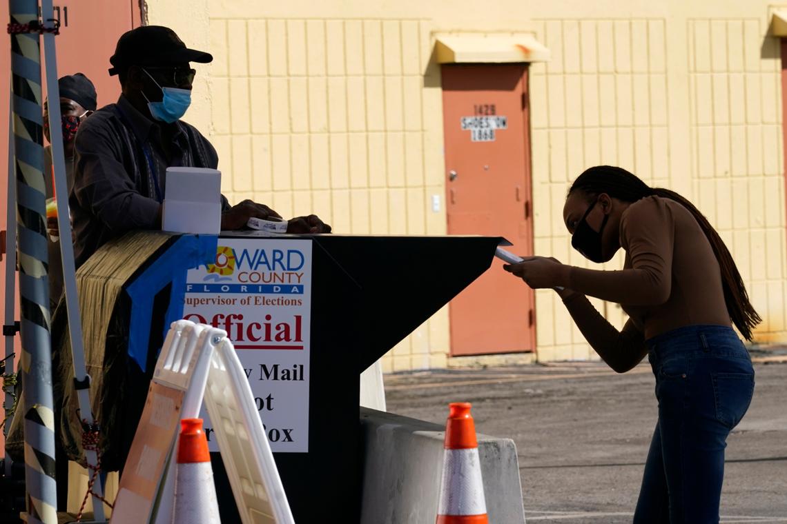 A woman drops a vote-by-mail ballot into a ballot drop box in Broward County in 2020.