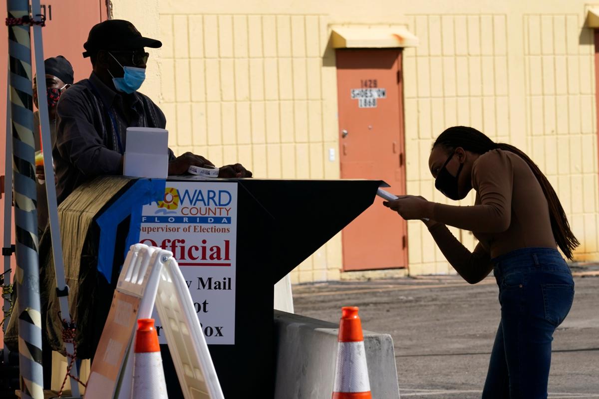 Una mujer deposita una papeleta de voto por correo en una urna del Condado Broward en 2020.