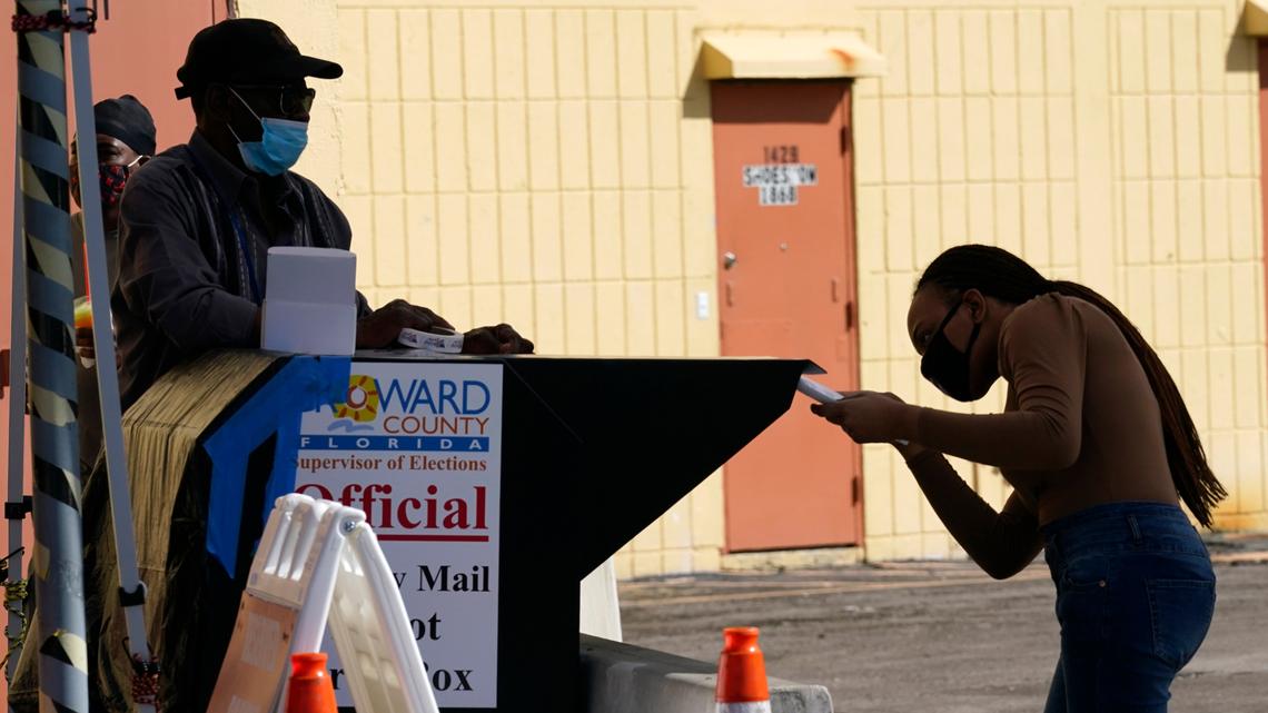 A woman drops a vote-by-mail ballot into a ballot drop box in Broward County in 2020.