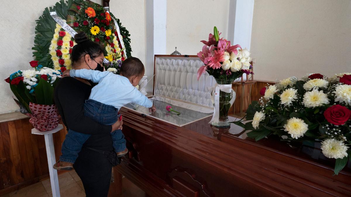 Un nieto se sostiene sobre el ataúd abierto que contiene los restos de su abuelo, el periodista asesinado Armando Linares, en Zitácuaro, en el estado de Michoacán, México, el miércoles 16 de marzo de 2022. (AP Foto/Marco Ugarte)